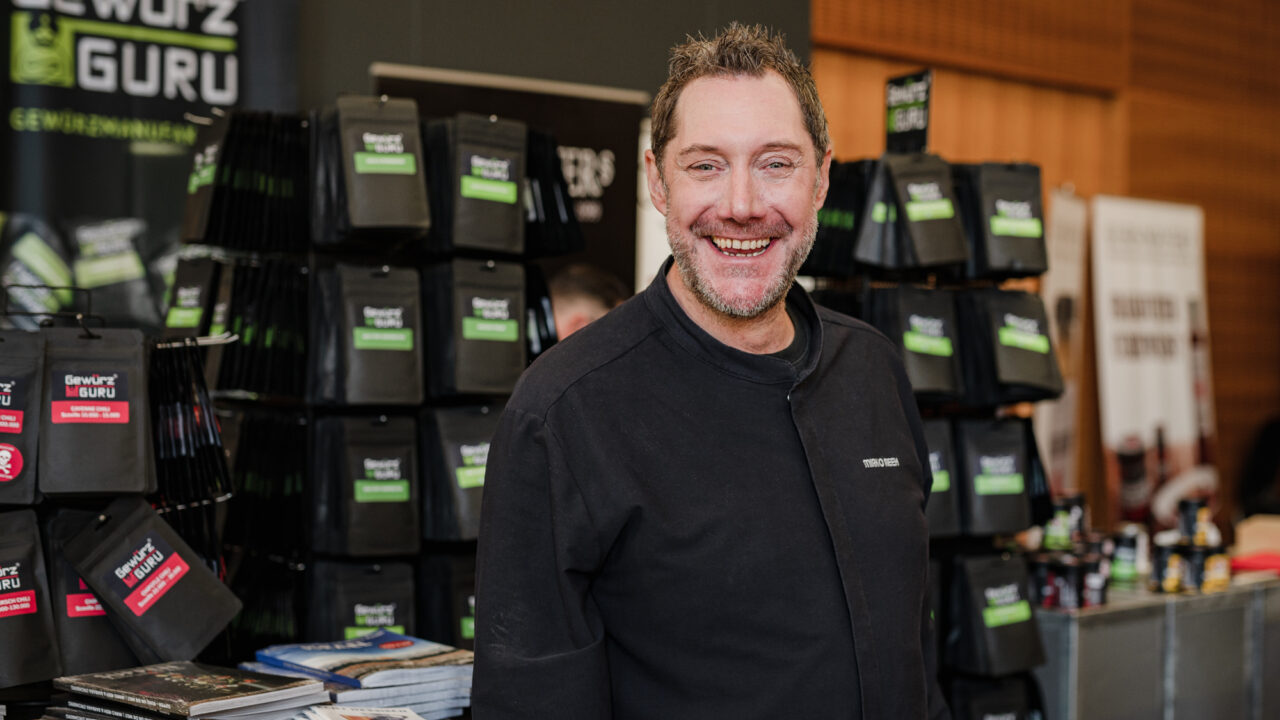 Foto: Starkoch Mirko Reeh präsentiert lächelnd seinen Messestand Gewürz Guru